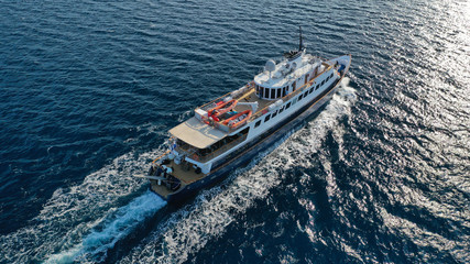Aerial drone photo of luxury yacht cruising near iconic village of Oia, Santorini island, Cyclades, Greece