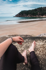 Close up of legs of young girl resting on the boulders on the beach, Australia