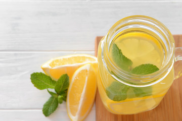 Jar of tasty lemonade on white wooden background