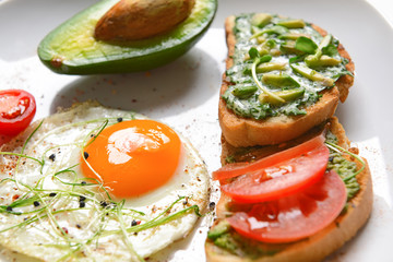 Tasty avocado sandwiches and fried egg on plate, closeup