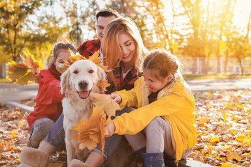 Happy family with dog resting in autumn park