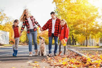 Happy family with dog walking in autumn park