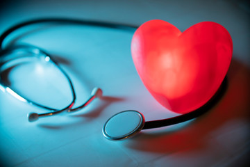Red heart with stethoscope on blue background. Copy space