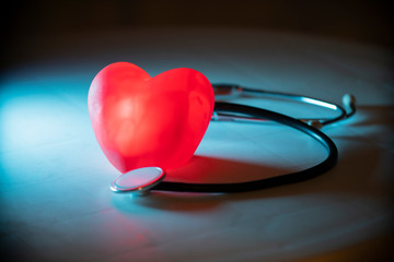 Red heart with stethoscope on blue background. Copy space