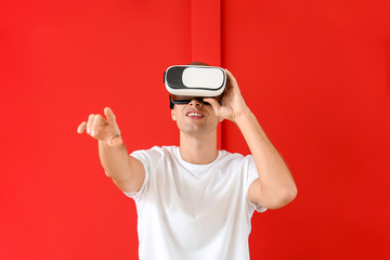 Young man with virtual reality glasses on color background