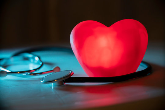 Red heart with stethoscope on blue background. Copy space