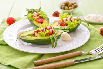 Plate with tasty tasty stuffed avocado on table