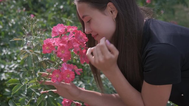 Girl in botanical garden. Beautiful young girl sniffing flowers in the garden.