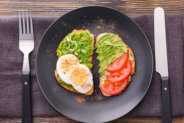 Plate with tasty avocado sandwiches on wooden table