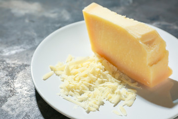 Plate with tasty Parmesan cheese on grey background