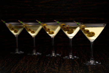 five glasses of  martini on a black background, selective focus.