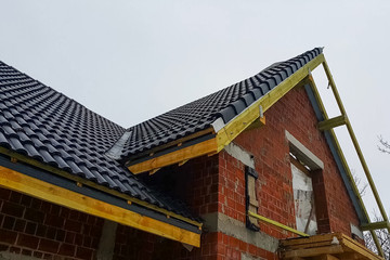 Installation of the roof of the house from ceramic black tiles.