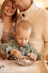 a young family dad, mom and their little son have a fun playing and cooking in the kitchen