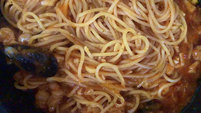 Chef cooking spaghetti seafood sauce. Prawns and mussels roasted on frying grill pan with garlic, parsley, white wine, cayenne, green sauce, lemon on in frying pan. Slow motion.