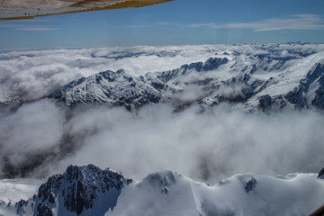 Fototapeta na wymiar vue aérienne à basse altitude, au-dessus du parc national mount aspiring, en nouvelle zélande, avec un magnifique ciel bleu, et des sommets enneigés