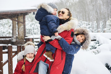 Obraz premium A young mother with her tree children have a fun and playing snowballs outdoor near the home