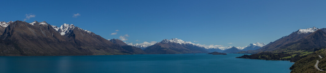 Naklejka na ściany i meble Vue panoramique du lac wakatipu, en nouvelle zélande, avec un ciel bleu sans nuages