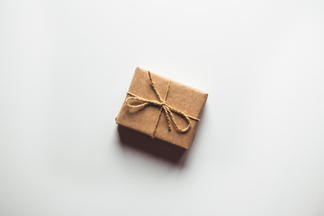 Gift box wrapped in brown recycled paper and tied sack rope top view isolated on white background
