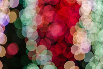 Red, green and pink Christmas light shiny abstract round bokeh on black background. Colourful Glitter bokeh from blurry decoration bulbs.