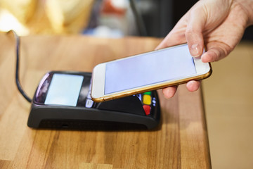 Close up hand paying order by credit card on payment terminal in the coffee shop