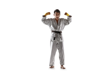 Obraz premium Confident korean man in kimono practicing hand-to-hand combat, martial arts. Young male fighter with black belt celebrates win isolated on white studio background. Concept of healthy lifestyle, sport.