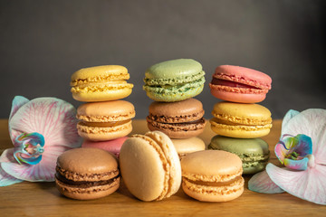Colorful macarons, orchid flowers put on wood table. Colorful macarons french dessert