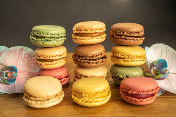 Colorful macarons, orchid flowers put on wood table. Colorful macarons french dessert