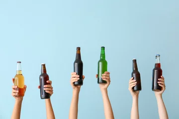 Gordijnen Hands with bottles of beer on color background © Pixel-Shot
