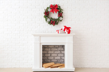 Beautiful Christmas wreath hanging on wall near fireplace with gift boxes