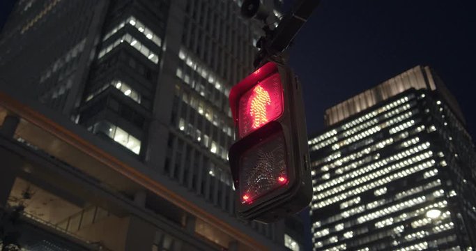 Traffic lights under buildings at night in Tokyo Japan.