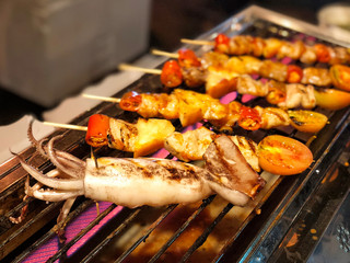 Squid chicken and pork and various vegetables on barbecue grill cooked