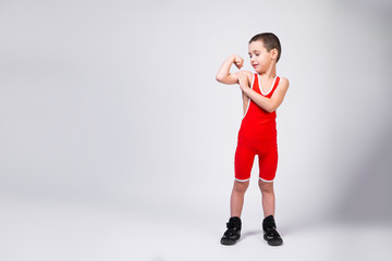  The concept of a little fighter athlete. Little funny boy watches his muscles grow on his arms and smiles at his achievements on a white isolated background © Виталий Сова