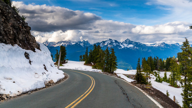 Washington, USA. Uphill road landscape in winter at Mount Baker. Asphalt road with sideways full of snow.