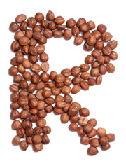 Letter R of the English alphabet from from hazelnut on a white isolated background. Food pattern made from nuts. Bright alphabet for shops.