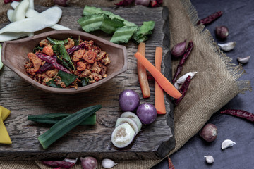 Fototapeta na wymiar Pork Crackling Chili Paste with fried kaffir lime leaves with the ingredient and fresh vegetables on wood background.