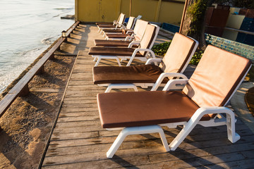 Rows of wooden deck chairs on an empty  by the pool.