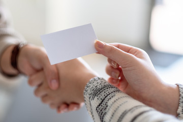 Two people shaking hands and exchanging empty business card