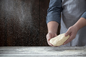  hands cooking dough on dark wooden background
