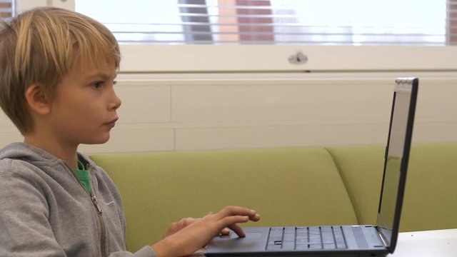 Static shot of a boy, focused, learning the use of a computer in education, in a classroom, at a school, in Finland
