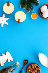 Ingredients for New Year drink eggnog - eggs, milk, cinnamon on blue background top view frame copy space
