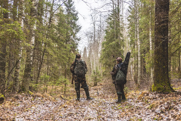 two men, in camouflage, in the woods, autumn, stand on a forest road and talking, with arms