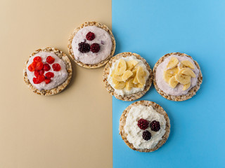 Dessert on blue and yellow background. Crispbread, cottage cheese and fruit