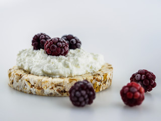 Dessert of crispbread, cottage cheese and juicy blackberries on a white background