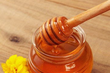 honey in a jar with dipper on wooden background