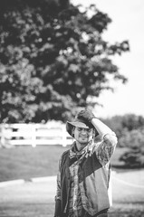 Vertical grayscale shot of a male wearing a cowboy outfit whit his hand on the hat