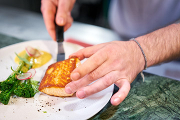 The chef serves the dish Salmon steak fillet and garnished with young broccoli. Restaurant menu, a series of photos of different dishes