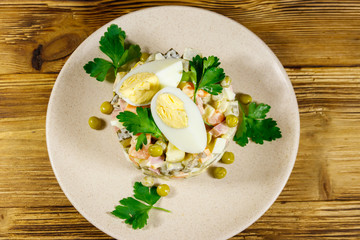 Traditional Russian festive salad Olivier on wooden table. Top view