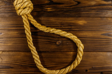 Obraz premium Deadly loop of rope on a wooden background. Concept of death penalty or suicide