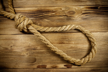 Obraz premium Deadly loop of rope on a wooden background. Concept of death penalty or suicide