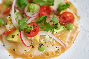 Fototapeta na wymiar Tartar from scallop with avocado, cherry tomatoes, radishes and onion. Dish in the restaurant from raw seafood.